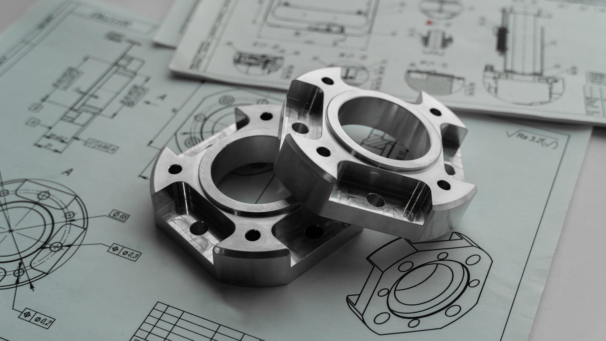 Machined metal parts resting on engineering drawings