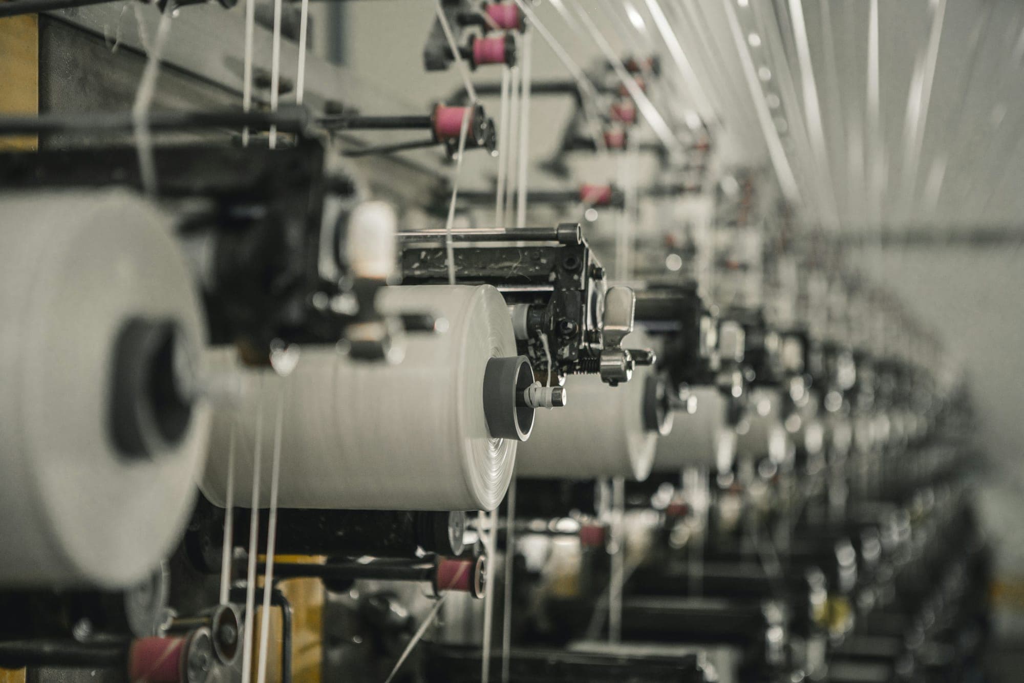 A row of industrial spinning machines with yarn spools